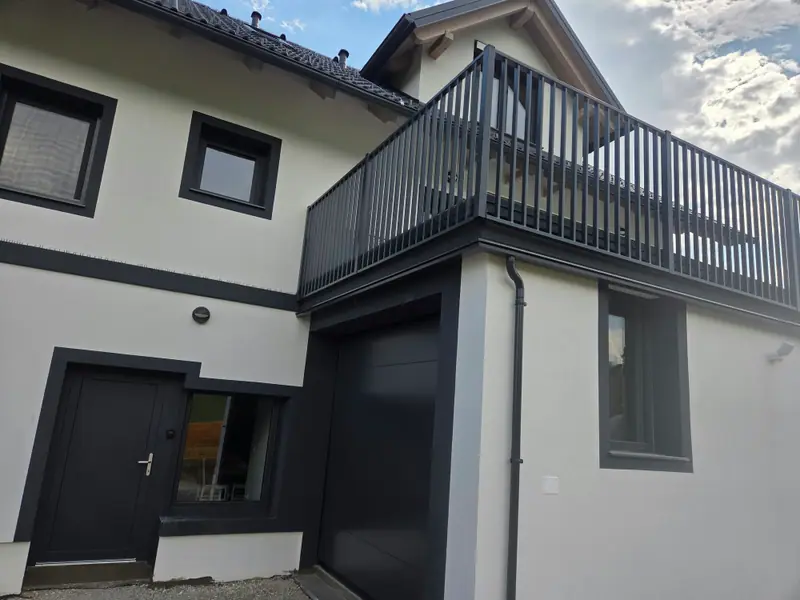 Balkonska ograja z vertikalnimi polnili nad vhodom in garažo sodobne hiše