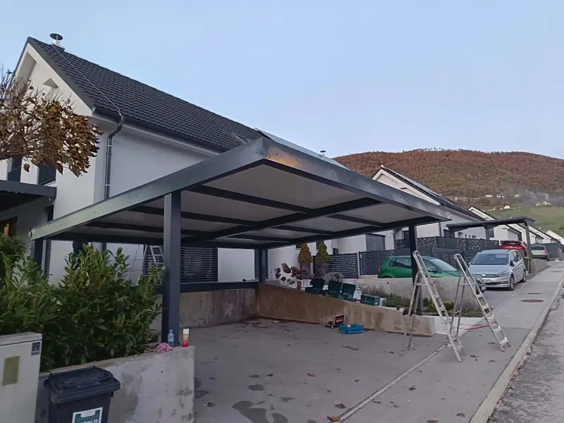 Kovinski nadstrešek za avtomobile ob stanovanjski hiši
