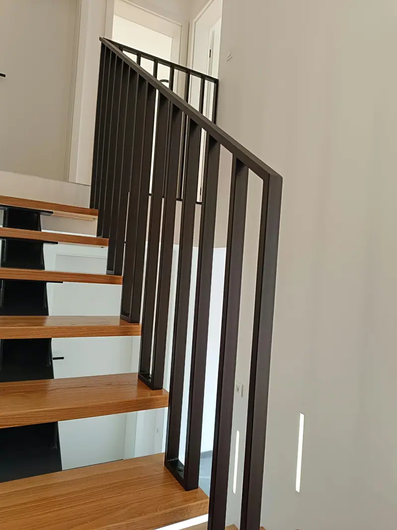 Stopniščna ograja z vertikalnimi palicami ob lesenih stopnicah
